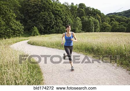 Stock Image - Mixed race woman running on path. Fotosearch