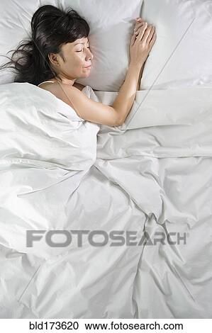 Stock Image - Mixed race woman sleeping in bed. Fotosearch