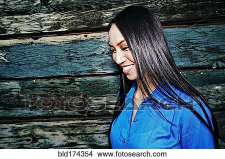 Picture - Mixed race woman smiling at wooden wall. Fotosearch