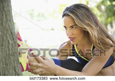 Stock Image - Mixed race woman stretching on tree. Fotosearch