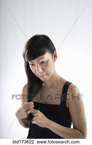 Stock Image - Mixed race woman twisting her hair. Fotosearch