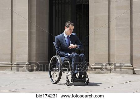 Stock Image - Paraplegic businessman in wheelchair checking watch. Fotosearch