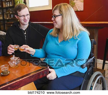 Stock Image - Paraplegic woman and boyfriend drinking tea. Fotosearch