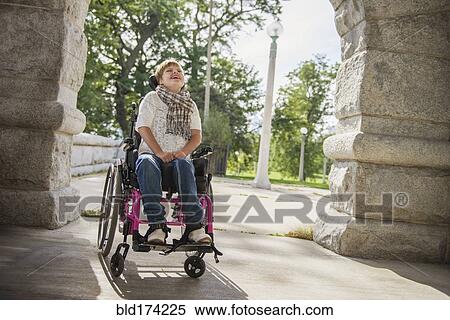 Stock Photography - Paraplegic woman in wheelchair under stone arch. Fotosearch