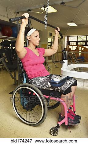 Stock Photo - Paraplegic woman in wheelchair working out in physical therapy. Fotosearch