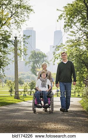 Parents pushing paraplegic daughter in wheelchair View Large Photo Image Stock Photograph - Parents pushing paraplegic daughter in wheelchair. Fotosearch