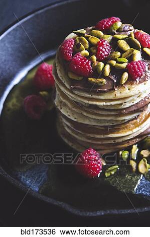 Stock Photograph - Pistachios and raspberries on pancakes. Fotosearch