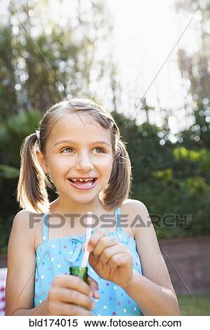 Smiling girl eating candy cigarette in backyard View Large Photo Image Stock Photography - Smiling girl eating candy cigarette in backyard. Fotosearch