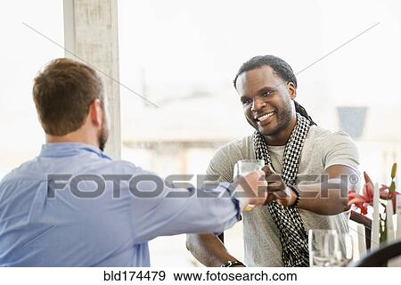Stock Photo - Smiling men toasting indoors. Fotosearch