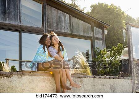 Stock Image - Smiling women hugging in backyard. Fotosearch