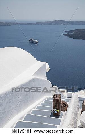 Stock Image - Suitcase on hillside steps over ocean. Fotosearch