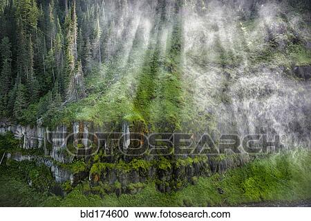 Stock Image - Sunbeams and clouds over remote hillside. Fotosearch