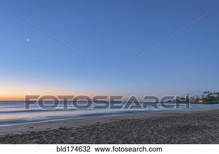 Stock Image - Sunrise over beach and ocean. Fotosearch