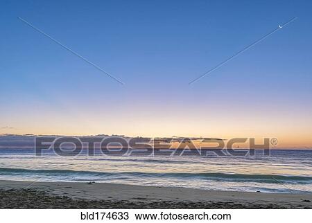 Stock Image - Sunrise over beach and ocean. Fotosearch