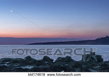 Sunrise over rock formations on beach View Large Photo Image Stock Photo - Sunrise over rock formations on beach. Fotosearch