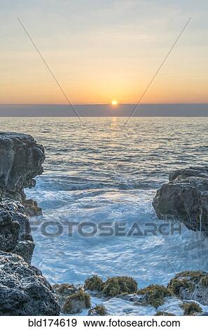 Sunrise over rock formations on beach View Large Photo Image Stock Photo - Sunrise over rock formations on beach. Fotosearch