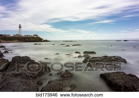 Stock Photograph - Time lapse view of ocean waves on rocky beach. Fotosearch