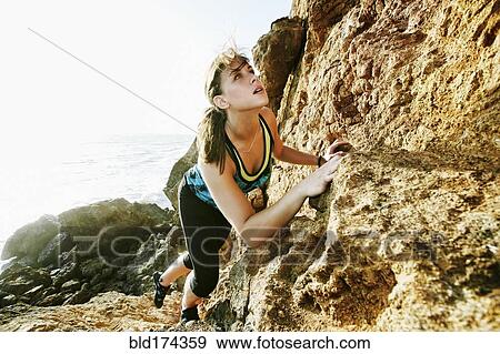 Stock Photo - Woman climbing on boulders. Fotosearch