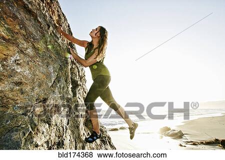 Stock Photo - Woman climbing rock formation. Fotosearch