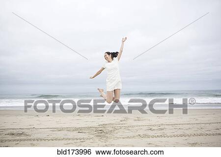 Stock Photograph - Woman jumping for joy on beach. Fotosearch