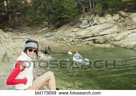 Stock Photo - Woman near boyfriend rowing kayak in lake. Fotosearch