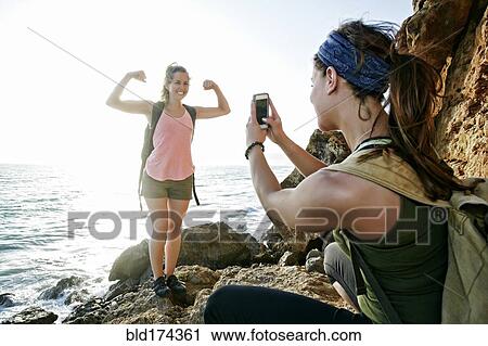 Woman photographing friend outdoors View Large Photo Image Stock Image - Woman photographing friend outdoors. Fotosearch