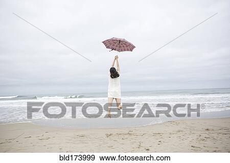 Woman playing with umbrella on beach View Large Photo Image Stock Photo - Woman playing with umbrella on beach. Fotosearch