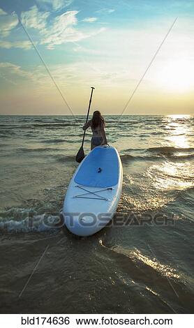 Woman pulling paddleboard in lake View Large Photo Image Stock Photograph - Woman pulling paddleboard in lake. Fotosearch