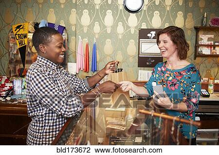 Woman serving customer in store View Large Photo Image Stock Image - Woman serving customer in store. Fotosearch