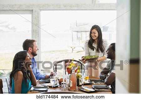 Picture - Woman serving friends at dinner party. Fotosearch