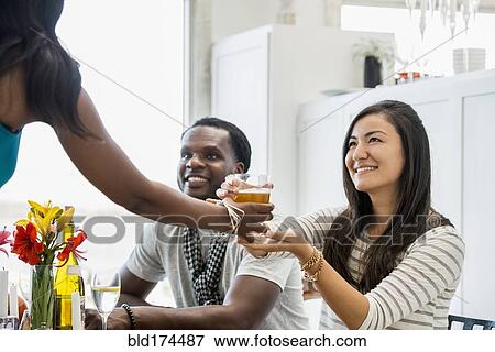 Stock Photo - Woman serving friends at dinner party. Fotosearch