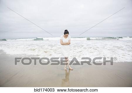 Woman standing near waves on beach View Large Photo Image Stock Image - Woman standing near waves on beach. Fotosearch