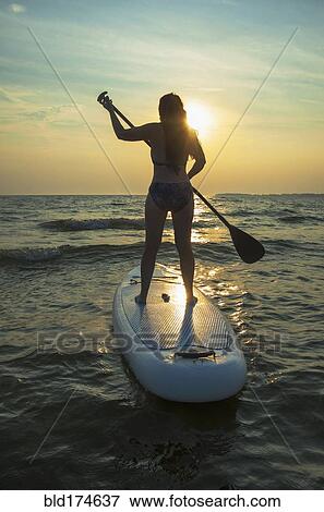Woman standing on paddleboard in lake View Large Photo Image Stock Photo - Woman standing on paddleboard in lake. Fotosearch