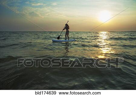 Woman standing on paddleboard in lake View Large Photo Image Stock Photo - Woman standing on paddleboard in lake. Fotosearch