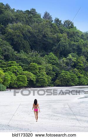 Stock Image - Woman walking on beach. Fotosearch