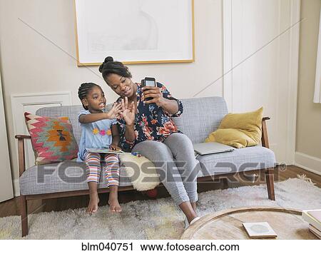 African American mother and daughter taking selfie in living room View Large Photo Image Stock Image - African American mother and daughter taking selfie in living room. Fotosearch