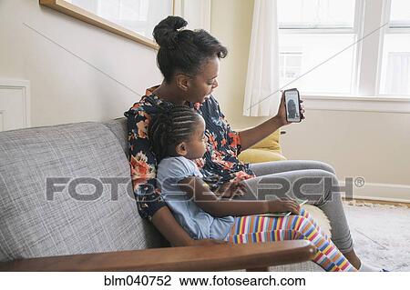 Stock Image - African American mother and daughter video chatting on cell phone. Fotosearch