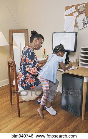Stock Photograph - African American mother with daughter working from home. Fotosearch