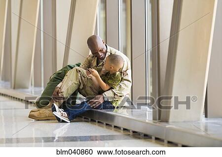 Stock Image - African American soldier and son talking in airport. Fotosearch