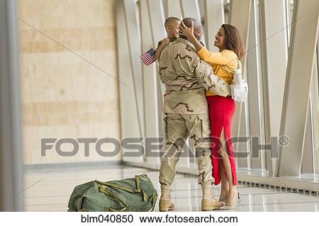 Stock Image - African American soldier greeting family in airport. Fotosearch