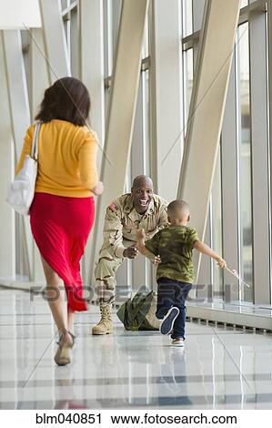 Stock Image - African American soldier greeting family in airport. Fotosearch