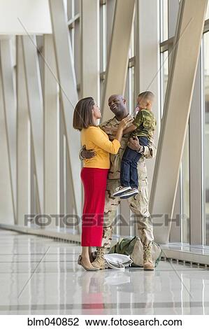 Stock Image - African American soldier greeting family in airport. Fotosearch