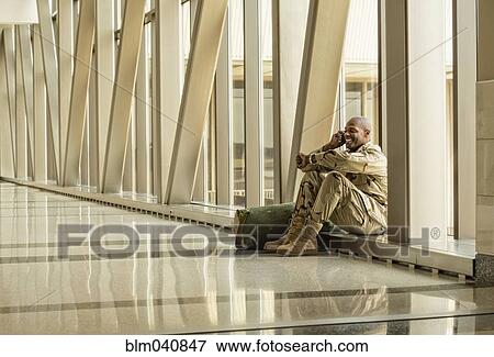 Stock Photo - African American soldier talking on cell phone in airport. Fotosearch