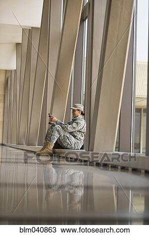 Stock Image - African American soldier using cell phone in airport. Fotosearch