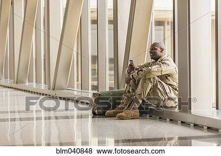 Stock Photo - African American soldier using cell phone in airport. Fotosearch