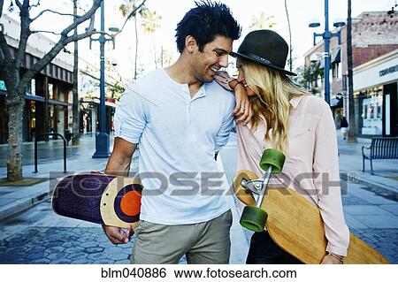 Stock Photograph - Caucasian couple carrying skateboards. Fotosearch