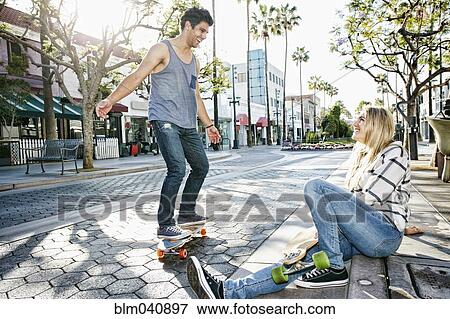 Caucasian couple riding skateboards View Large Photo Image Stock Photo - Caucasian couple riding skateboards. Fotosearch