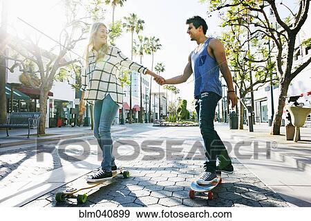 Stock Photo - Caucasian couple riding skateboards. Fotosearch