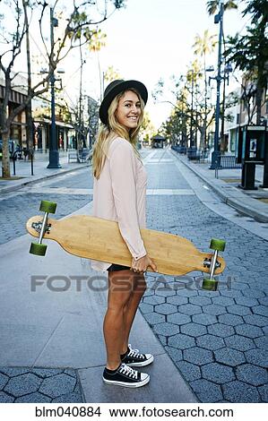 Picture - Caucasian woman carrying skateboard. Fotosearch
