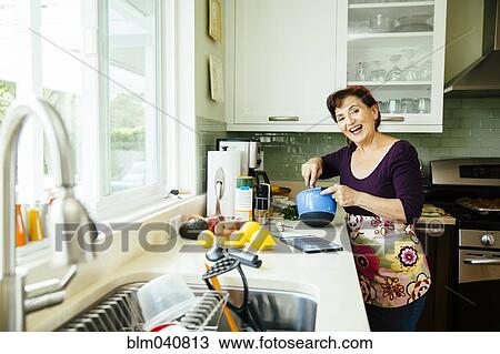 Stock Image - Caucasian woman cooking in kitchen. Fotosearch
